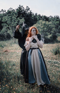 Woman with arms raised standing on field