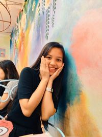 Portrait of smiling girl sitting against wall