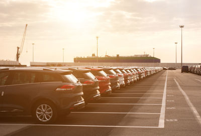 Cars in parking lot by street against sky