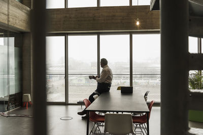 Senior manager in office holding cup of coffee, looking serious