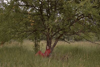 Woman standing by tree on field