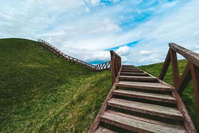 Steps on hill against cloudy sky