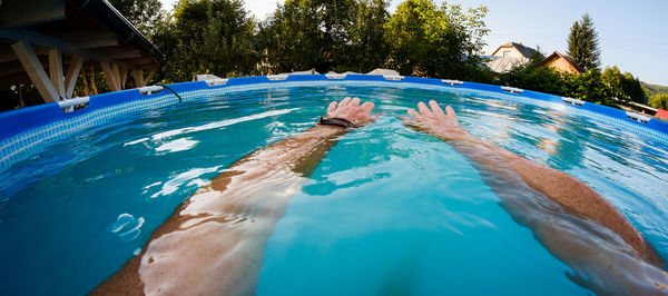 Cropped hands of man in wading pool at yard