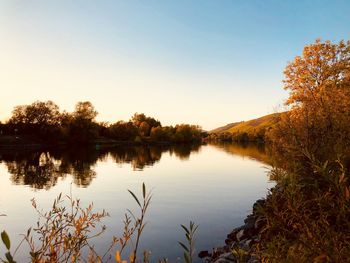 Scenic view of lake against clear sky during sunset