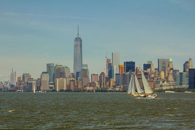 Sailboats in city at waterfront against sky