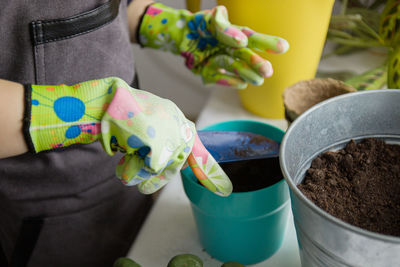 Children's hands in gloves pour the ground into the pot