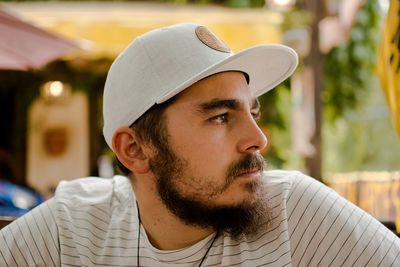 Close-up of handsome young bearded man wearing cap