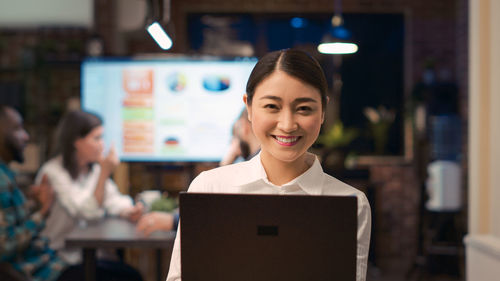 Portrait of young businesswoman using digital tablet while standing in library