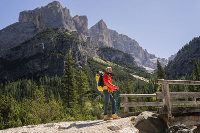 Hiker with backpack standing in front of dolomites, italy