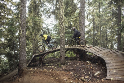 Friends riding mountain bikes on boardwalk in forest