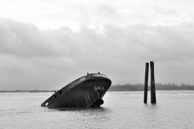 Abandoned boat in sea against sky