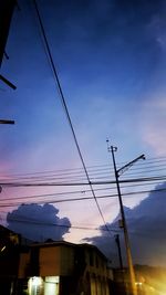 Low angle view of silhouette electricity pylon against sky at sunset