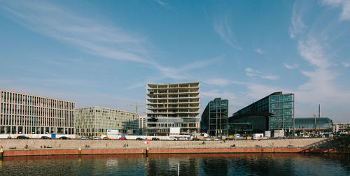 Buildings by river against sky in city