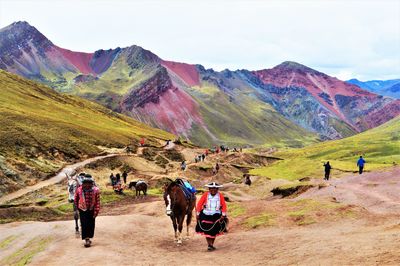 People walking on landscape against mountains