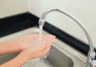 Cropped image of woman hand holding faucet at home