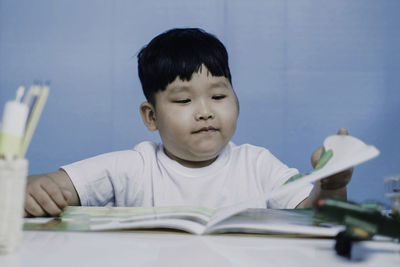 Portrait of boy with open book on table