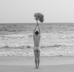 Rear view of woman standing at beach