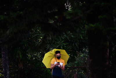 Young man holding umbrella standing outdoors