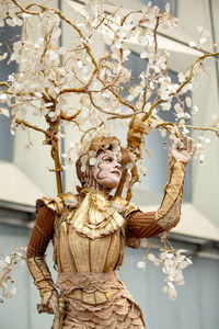 Low angle view of angel statue by tree