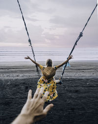 Rear view of man holding sea against sky