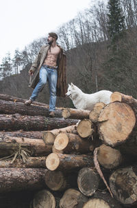 Full length of man standing on log in forest