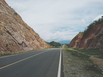 Empty road by mountains against sky