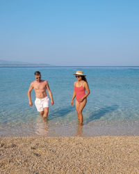 Rear view of woman standing at beach against clear sky