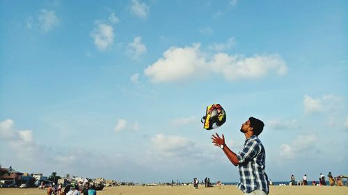 Man throwing helmet against sky