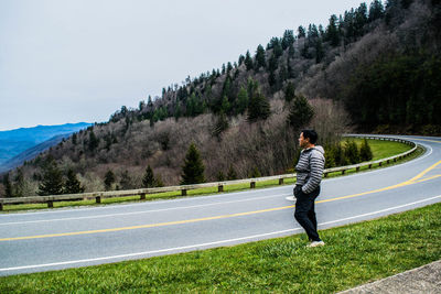 Side view of man standing on road against sky