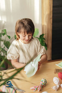 A girl at home prepares fabric for making easter textile eggs in the shape of a hare with ears. 