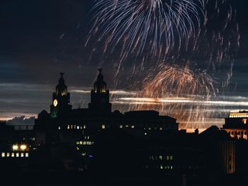 Firework display in city against sky at night