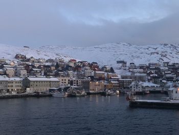 Aerial view of townscape by sea against sky