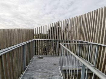 Fence by footpath against sky