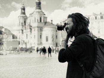 Side view of young man photographing in city