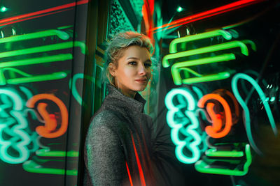 Portrait of woman standing against illuminated lights