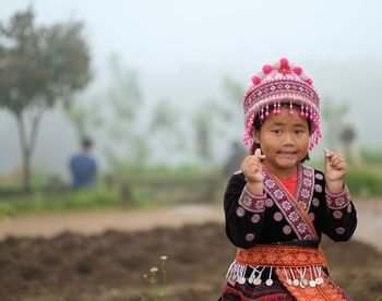 Portrait of cute girl in traditional clothing standing against sky