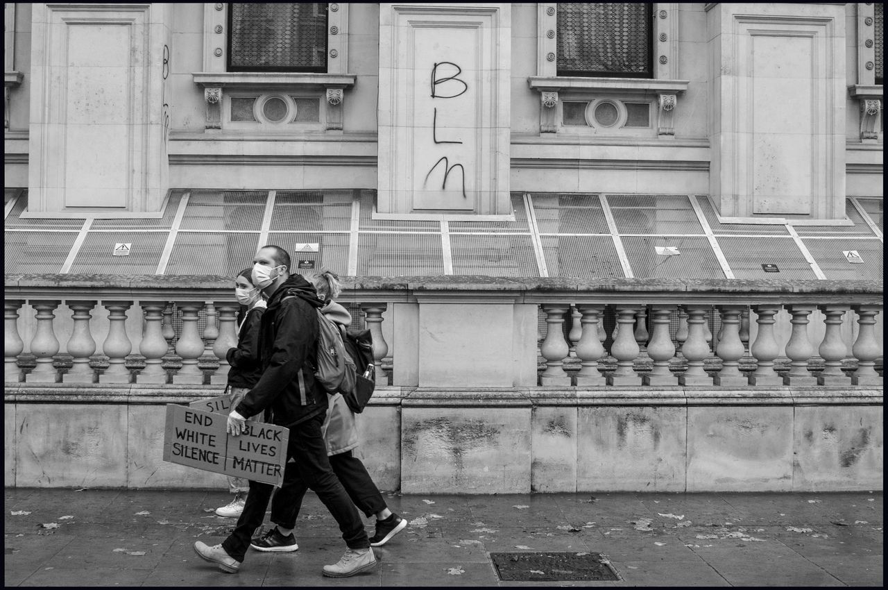 black and white, architecture, full length, street, monochrome, black, monochrome photography, one person, road, built structure, building exterior, city, adult, transfer print, men, lifestyles, day, auto post production filter, person, clothing, walking, women, leisure activity, white, outdoors, casual clothing, standing, footwear