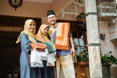 Portrait of smiling family with carpet standing outside
