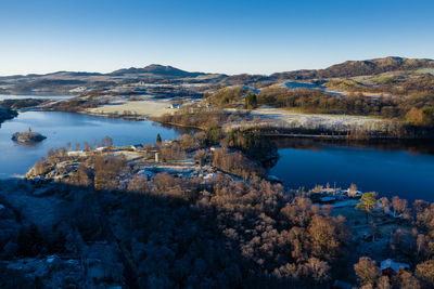 Scenic view of lake by mountains against clear blue sky