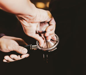 Close-up of person holding hands against black background