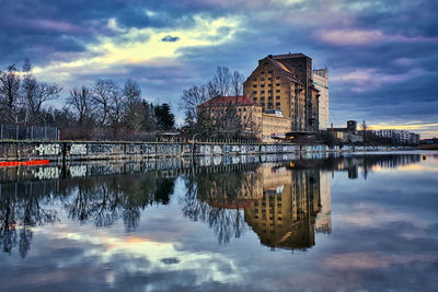 Reflection of buildings in lake against sky at sunset