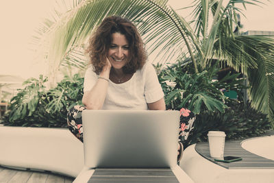 Young woman using phone while sitting on table