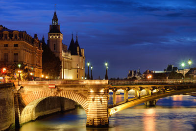 Arch bridge over river against buildings in city