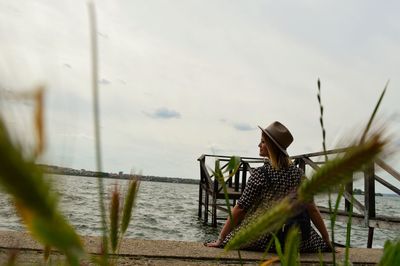 Woman in hat by sea against sky