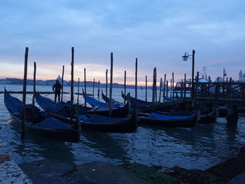 Boats moored in sea against cloudy sky