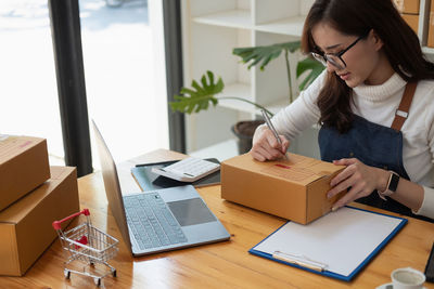 Side view of woman using laptop at office