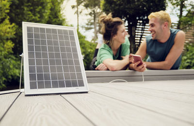 Woman with boyfriend charging smart phone with solar panel