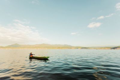 Man in boat on lake against sky