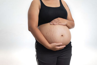 Midsection of woman touching face against white background