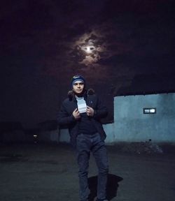 Full length portrait of man standing on illuminated mobile phone at night